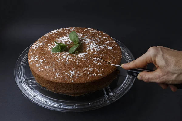 Mulher cortando um bolo de chocolate com decoração de açúcar com uma faca — Fotografia de Stock