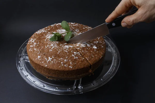 Mulher cortando um bolo de chocolate com decoração de açúcar com uma faca — Fotografia de Stock