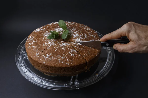 Mulher cortando um bolo de chocolate com decoração de açúcar com uma faca — Fotografia de Stock