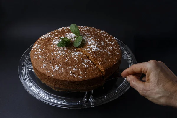 Mulher que serve um bolo de chocolate com decoração de açúcar com uma espátula — Fotografia de Stock