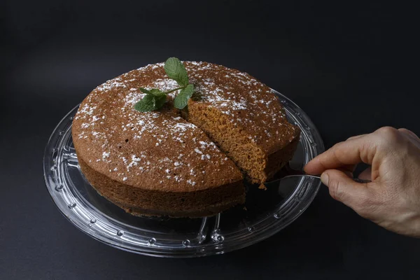 Mulher que serve um bolo de chocolate com decoração de açúcar com uma espátula — Fotografia de Stock