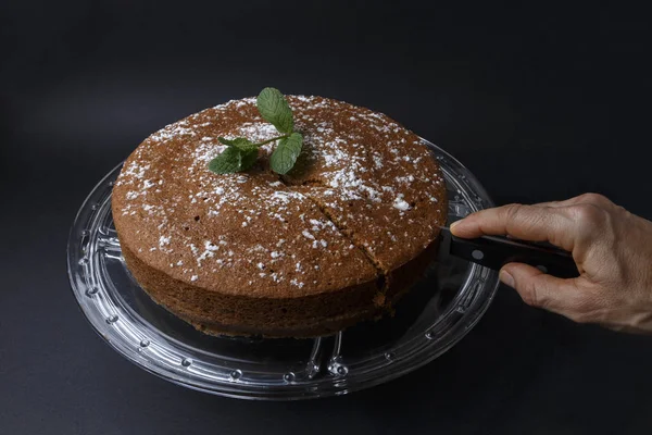 Mulher cortando um bolo de chocolate com decoração de açúcar com uma faca — Fotografia de Stock