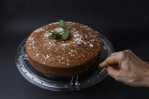 Mulher que serve um bolo de chocolate com decoração de açúcar com uma espátula — Fotografia de Stock