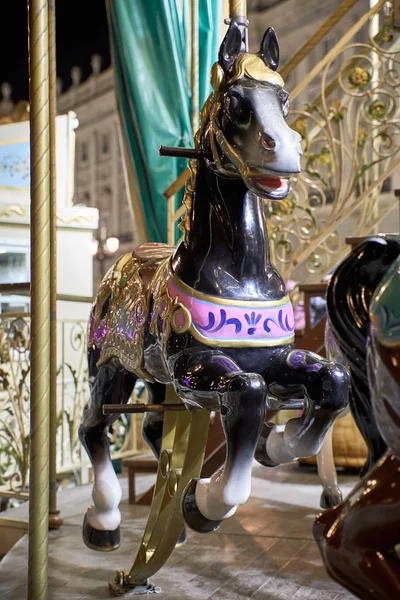 Caballos en un carrusel con luces en una noche de Navidad — Foto de Stock