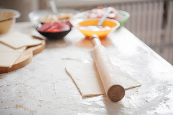 Sul tavolo la farina della mano del cuoco stendere l'impasto, gli ingredienti . — Foto Stock