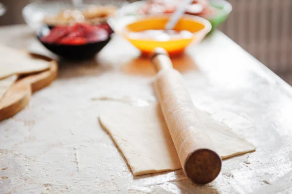 Sul tavolo la farina della mano del cuoco stendere l'impasto, gli ingredienti . — Foto Stock