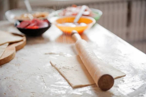 Az asztalon a lisztet, a kéz, a szakács zsemlye ki a tésztát, az összetevők. — Stock Fotó
