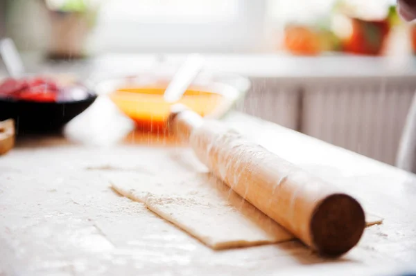 Sur la table, la farine de la main du cuisinier rouler la pâte, les ingrédients . — Photo