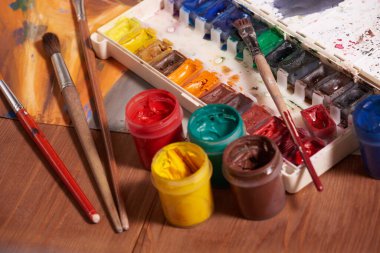 Bıyık boyalarıyla yapılmış usta bir çizim, natürmort. Boya kutuları ve fırçalar ustanın eli..