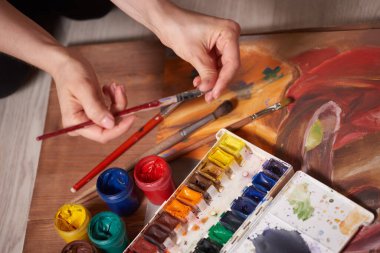 Bıyık boyalarıyla yapılmış usta bir çizim, natürmort. Boya kutuları ve fırçalar ustanın eli..