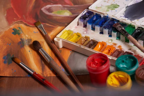 Bıyık boyalarıyla yapılmış usta bir çizim, natürmort. Boya kutuları ve fırçalar ustanın eli..