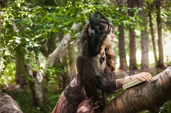 Bahçede yürüyen genç bir kadın. O, eski moda elbise ve peçeli şapka giyiyor. Ağaçlar ve yeşilliklerle çevrili.