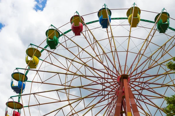 Fragment of a ferris wheel on a cloudy sky background