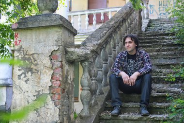 Adam terk edilmiş merdivenlerde oturuyor.