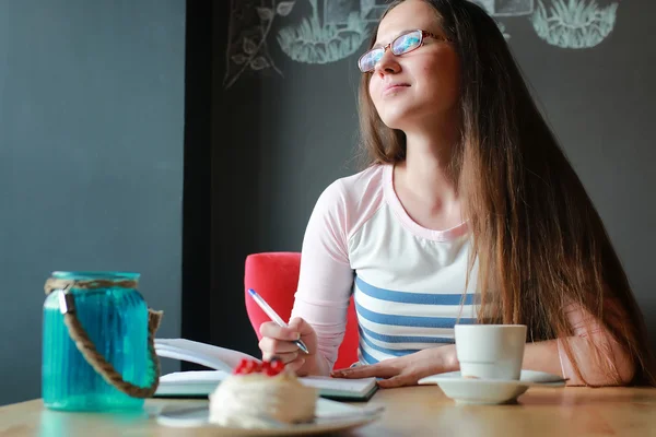 Mädchen in einem Café für eine Tasse Kaffee mit dem Notizbuch — Stockfoto