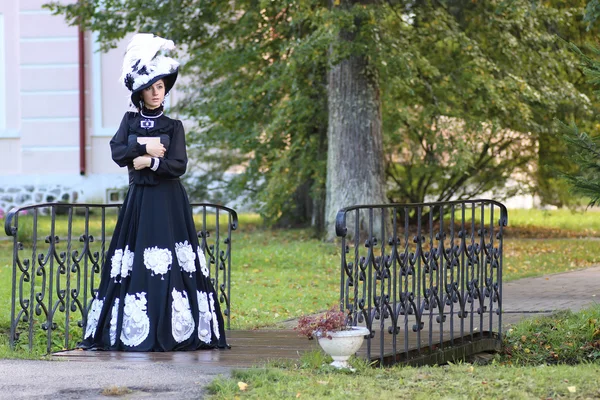 Renaissance vrouw met boek over de brug in park — Stockfoto