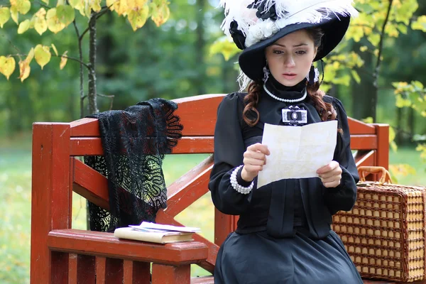 Menina em vestido retro século passado ler carta no banco — Fotografia de Stock