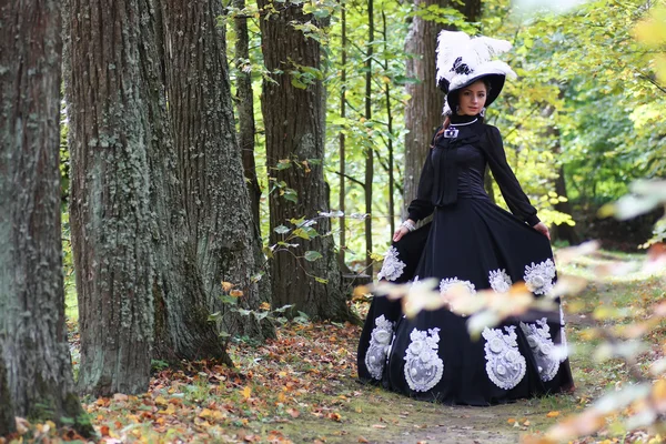 Dame in retro jurk wandelen in bomen steegje — Stockfoto