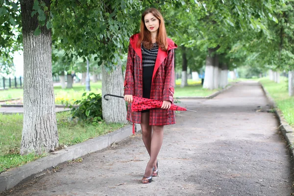 Frau mit rotem Regenschirm an Straßenbaum — Stockfoto