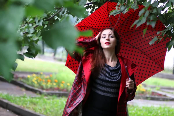 Vrouw in een regenjas en een paraplu — Stockfoto