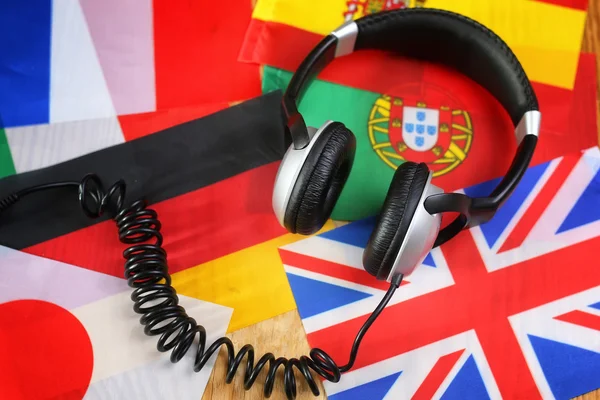 Auriculares y bandera del idioma del curso en una mesa —  Fotos de Stock