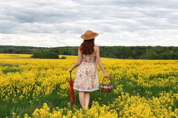 Девушка в поле цветов с зонтиком и шляпой — стоковое фото