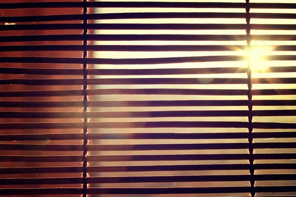 Abbagliamento dalla luce solare brillante attraverso le tende Rom in legno — Foto Stock