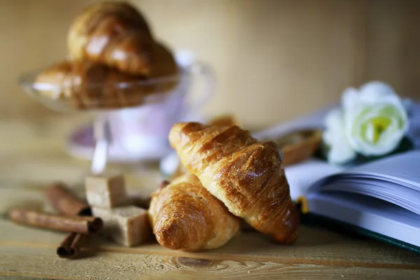 Tasse avec croissant de thé livre — Photo