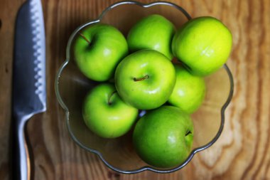 bir cam kase ahşap arka planda yeşil elma