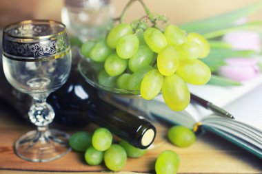 üzüm ve şarap şişesi kitap ile ahşap masa