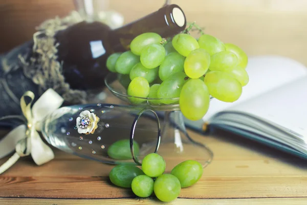 Table en bois avec bouteille de vin livre et raisin — Photo