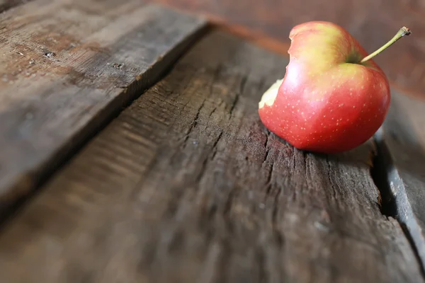 Nadgryzione jabłko na podłoże drewniane — Zdjęcie stockowe