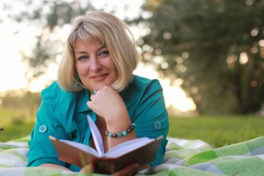 kadınla çimenlerin üzerinde kitapla Park