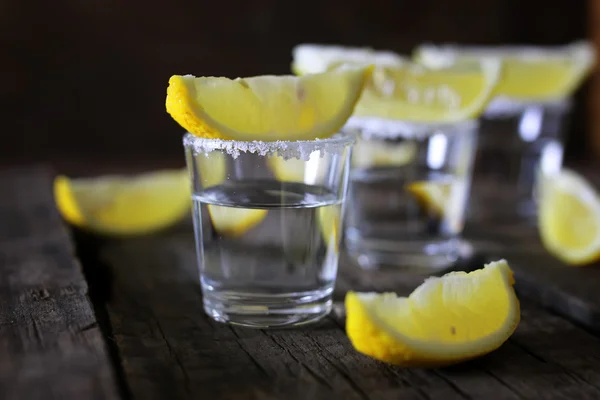 Pilha de tequila com sal e limão em um fundo de madeira — Fotografia de Stock