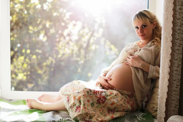 Pregnant woman on the windowsill — Stock fotografie