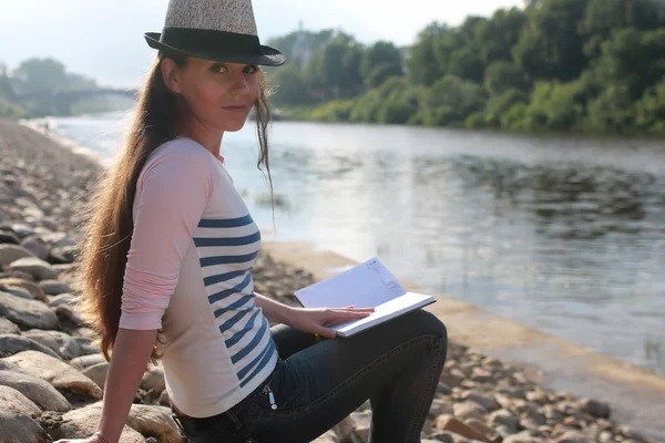 Flicka utomhus läsa bok sten flod — Stockfoto