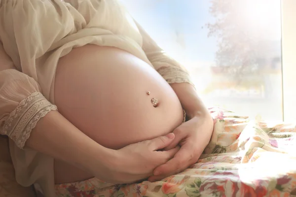 Pancia donna incinta vicino alla finestra — Foto Stock