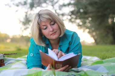 kadınla çimenlerin üzerinde kitapla Park