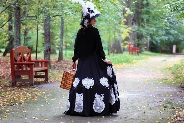 Meisje in de 18e eeuw retro jurk met valise in park — Stockfoto
