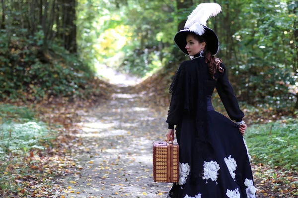 Meisje in de 18e eeuw retro jurk met valise in park — Stockfoto