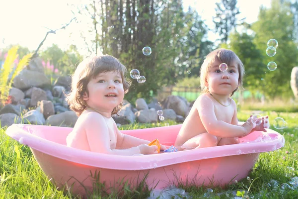 Gemelos chico y chica en baño agua al aire libre — Foto de Stock