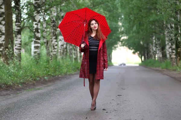 Donna con un impermeabile e un ombrello — Foto Stock