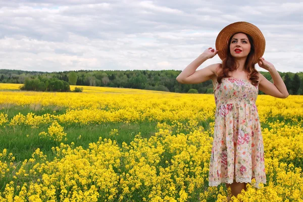 Niña en un campo de flores con cesta y sombrero — Foto de Stock