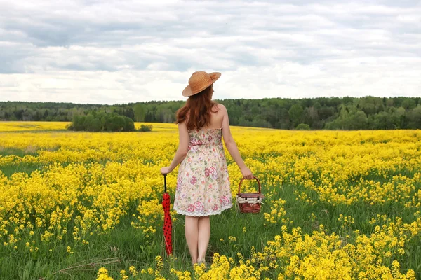 Девушка в поле цветов с зонтиком и шляпой — стоковое фото