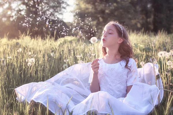 Menina em branco vestido sopro dundelion — Fotografia de Stock