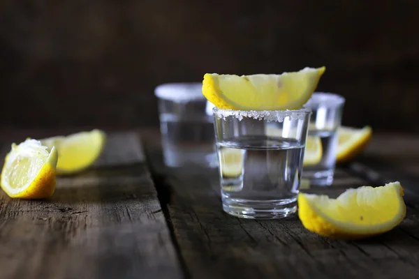 Stack of tequila with salt and lemon on a wooden background — Stock Photo, Image
