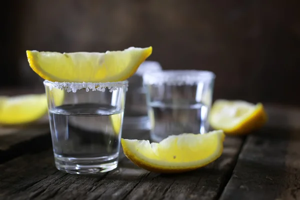 Pilha de tequila com sal e limão em um fundo de madeira — Fotografia de Stock