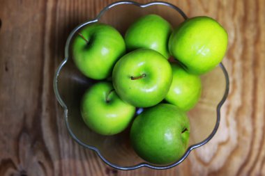 bir cam kase ahşap arka planda yeşil elma