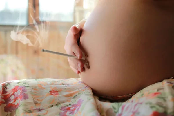 Беременная женщина курит сигарету — стоковое фото