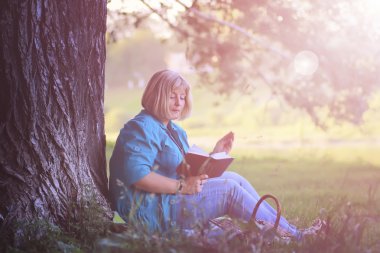 kadın parkta günbatımı kitap ile